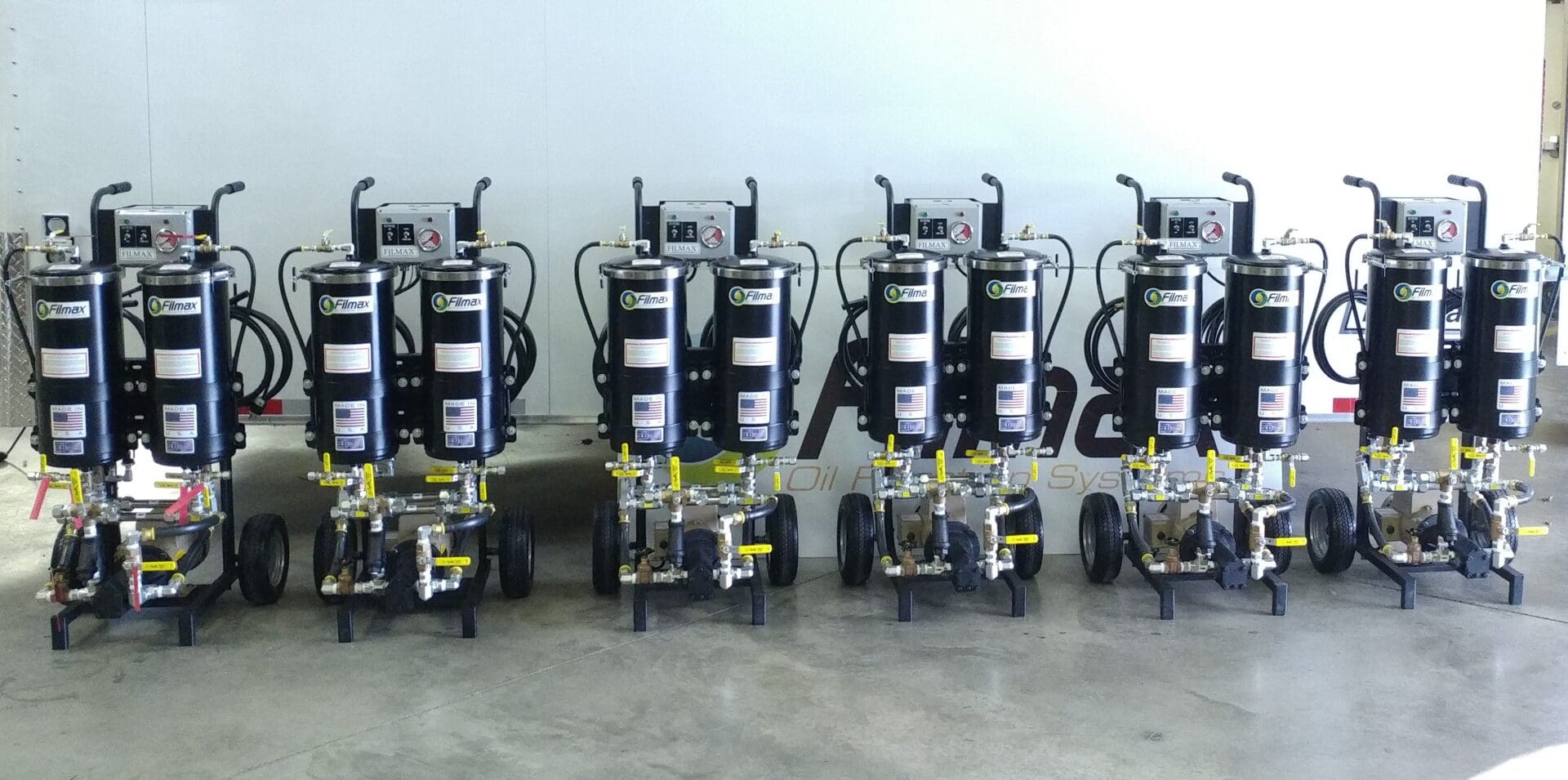 Four identical portable machines with gauges and hoses arranged in a row.